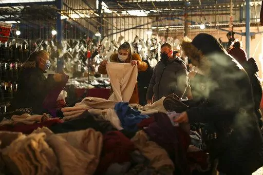 Bulgarian tourists shop at a bazaar in Edirne, near Bulgaria border, in Turkey, Friday, Dec. 24, 2021. Bulgarian shoppers are crossing Turkey’s western border in packed cars and buses, taking advantage of a declining Turkish lira to fuel their own shopping sprees. Their first stop is the currency exchange and then it's off to the markets and grocery stores in the northwestern city of Edirne. (AP Photo/Emrah Gurel)