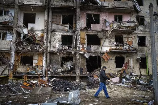 A man walks past a building damaged following a rocket attack, in Kyiv, Ukraine, Friday, Feb. 25, 2022.  The International Criminal Court's prosecutor has put combatants and their commanders on notice that he is monitoring Russia's invasion of Ukraine and has jurisdiction to prosecute war crimes and crimes against humanity. But, at the same time, Prosecutor Karim Khan acknowledges that he cannot investigate the crime of aggression. (AP Photo/Emilio Morenatti, File)