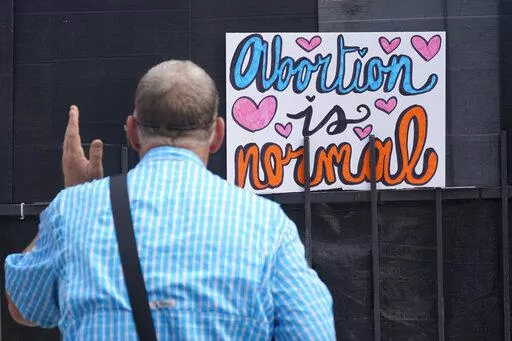 Anti-abortion activist Coleman Boyd, faces a new sign stating that "Abortion is normal," as he preaches outside the Jackson Women's Health Organization clinic in Jackson, Miss., Thursday, June 30, 2022. (AP Photo/Rogelio V. Solis)