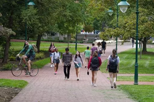 Students walk to and from classes on the Indiana University campus, Thursday, Oct. 14, 2021, in Bloomington, Ind. Between fall 2019 and 2021, college enrollment nationwide fell by nearly a million students — and for a number of financial reasons, this fall is an ideal time for students to resume their education to attain a degree or credential. The advantage of earning a degree is still evident since higher education typically results in bigger lifetime earnings and postponing your education m
