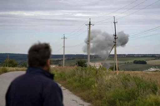 Viktor Lubinets, an agronomist at the Veres farm, looks at smoke rising in the air following a explosion in Novomykolaivka, eastern Ukraine, Saturday, Sept. 10, 2022. Returning to sowing and harvesting "will be difficult, very difficult," said Lubinets, an agronomist at the Veres farm. Even if the fighting ends, the fields must be cleared of unexploded ordinance and shrapnel before they can be worked. (AP Photo/Leo Correa)