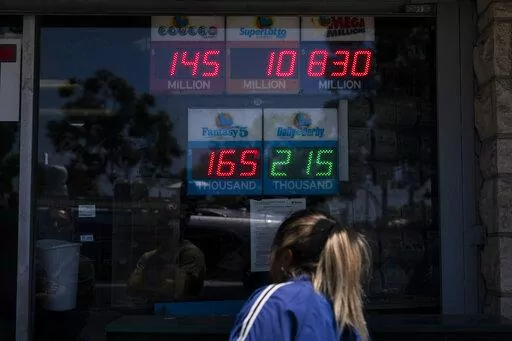 A woman peeks through the window of Blue Bird Liquor while waiting in line to purchase a Mega Millions lottery ticket in Hawthorne, Calif., Tuesday, July 26, 2022. Lottery players will be gripping their tickets tightly ahead of the Tuesday night's Mega Millions drawing with an estimated $830 million prize on the line. AP Photo/Jae C. Hong)