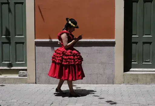 A woman looks at her phone as she walks in La Paz, Bolivia, Wednesday, Feb. 26, 2025. (AP Photo/Juan Karita)