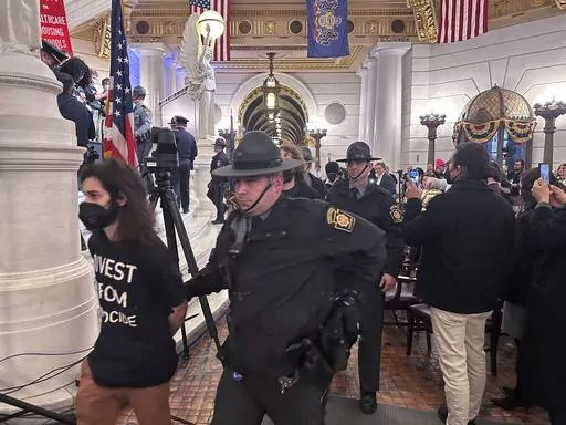 Police arrest some of about 200 people taken into custody on Monday, Feb. 5, 2024, in the Rotunda of the State Capitol in Harrisburg, Pennsylvania. The arrests shut down a demonstration against the state Treasury Department's investment of about $56 million in Israel bonds. The protest was organized by Jewish Voice for Peace, the Philly Palestine Coalition and the Pennsylvania Council on American-Islamic Relations. (AP Photo/Mark Scolforo)