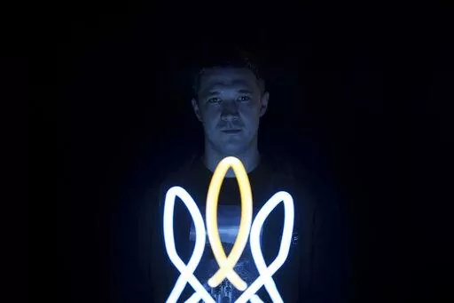 Mykhailo Fedorov, Ukrainian minister of digital transformation, poses for a photo illuminated by a lamp in the shape of a Ukrainian trident, a national symbol, in his office in Kyiv, Ukraine, Wednesday, Dec. 21, 2022. The Ukrainian government minister in charge of technology says his country has bought some 1,400 drones, mostly for reconnaissance, and is now developing air-to-air combat ones that can attack the drones Russia is using against Ukrainians. In a recent interview with The Associated 