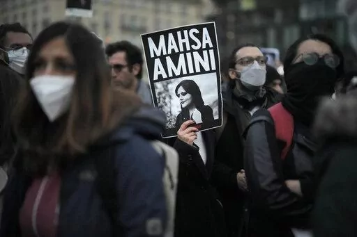 A woman shows a placard with a photo of of Iranian Mahsa Amini as she attends a protest against her death, in Berlin, Germany, Wednesday, Sept. 28, 2022.  Amini's death in custody has sparked a stunning wave of protests across Iran, with women removing headscarves. A cousin, Irfan Mortezai, says the family is proud that Amini has become a symbol of resistance, but they are lying low out of worries over Iranian security agents. (AP Photo/Markus Schreiber, File)