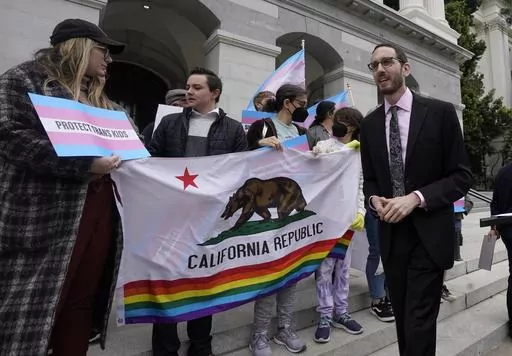 State Sen. Scott Wiener, D-San Francisco, right, prepares to announce his proposed measure to provide legal refuge to displaced transgender youth and their families during a news conference in Sacramento, Calif., on March 17, 2022. San Francisco is repealing a ban on city-funded travel to 30 states that it says restrict abortion, voting and LGBTQ rights after determining the boycott is doing more harm than good. Wiener, a former supervisor-turned-state senator who authored the original ban, agre