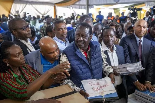 Presidential candidate Raila Odinga, center, hands over the petition to the Supreme Court challenging the election results, accompanied by running mate Martha Karua, left, in Nairobi, Kenya Monday, Aug. 22, 2022. Kenya's losing presidential candidate Odinga filed the Supreme Court challenge to last week's election results Monday, starting the 14-day period in which the court must rule. (AP Photo/Ben Curtis)
