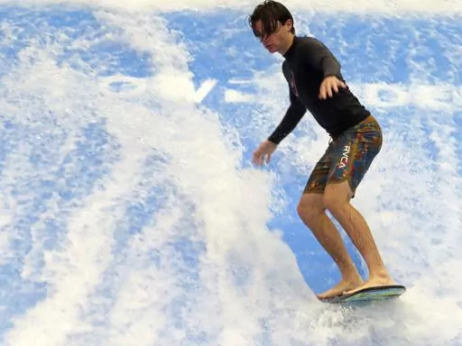 A man rides a surfboard on a surfing simulator during a preview of the Island Waterpark in Atlantic City, N.J., Thursday, June 22, 2023. The $100 million park, which will open June 30, is part of an effort by Atlantic City to offer guests — particularly those with children — something to do other than gambling. It's a strategy Las Vegas has been using to great effect. (AP Photo/Wayne Parry)