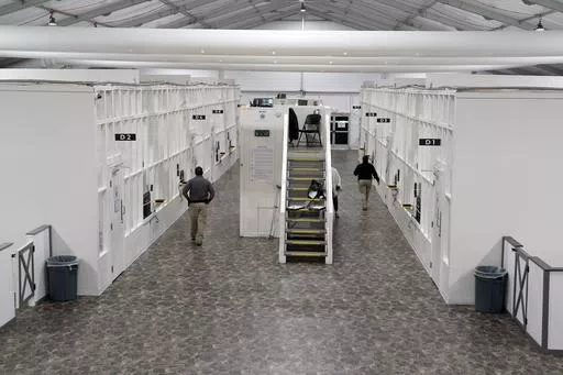 Agents walk among rooms at a Border Patrol holding facility on Dec. 15, 2023, in Tucson, Ariz. U.S. asylum officers were instructed nearly a year ago to apply a higher screening standard on people who cross the border illegally to claim asylum after passing through another country. But they are too understaffed to have much impact. (AP Photo/Gregory Bull, File)