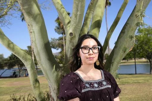 Olivia Yuen, 29, a middle school art teacher and well-known linocut artist in Phoenix, who has a Chinese father and a Mexican mother, stands under a palo verde tree Tuesday, May 21, 2024, in Laveen, Ariz. (AP Photo/Ross D. Franklin)
