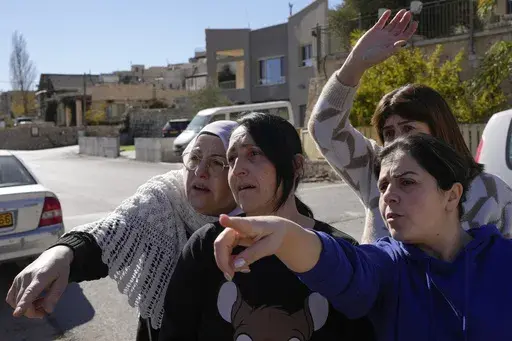 Soja Safadi, center, with her sisters, tries to see their other sister, Sawsan, who is inside the buffer zone near the "Alpha Line" that separates the Israeli-controlled Golan Heights from Syria, in the town of Majdal Shams, Wednesday, Dec. 18, 2024. (AP Photo/Matias Delacroix)