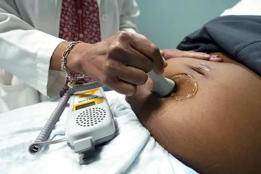 A doctor uses a hand-held Doppler probe on a pregnant woman to measure the heartbeat of the fetus on Dec. 17, 2021, in Jackson, Miss. U.S. births were flat in 2022, as the nation continues to see fewer babies born than before the pandemic. (AP Photo/Rogelio V. Solis, File)