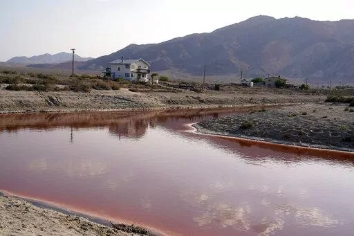 FILE— Clouds and nearby mountains are reflected in a polluted canal, once used as a boating dock, along the Salton Sea in Desert Shores, Calif., Wednesday, July 14, 2021. President Joe Biden on Tuesday, Feb. 22, 2022, pointed to plans to extract lithium from geothermal wastewater around the sea as an example of the Unites States' efforts to compete with China and other nations when it comes to domestic lithium production. The metal is a key element in rechargeable batteries, such as those used