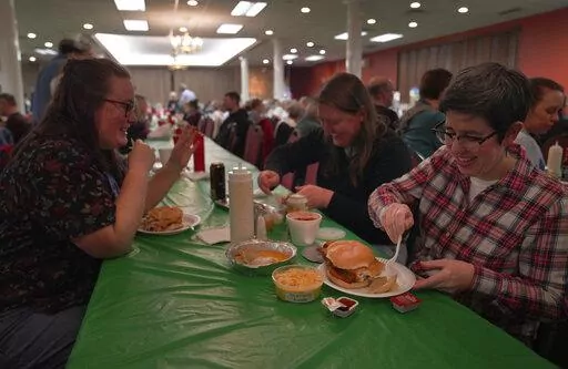 From left, Laura Kuster, Miranda Crotsley, and Hollen Barmer eat fish sandwiches, homemade perogies, and macaroni and cheese at the St. Maximilian Kolbe Catholic Church fish fry in the West Homestead neighborhood of Pittsburgh, on Friday, Feb. 24, 2023. To innovate the age-old tradition of fish fries, Barmer and volunteers from Code for Pittsburgh created the "Pittsburgh Lenten Fish Fry Map," an online interactive map that locates and documents active fish fries from year to year across Western 