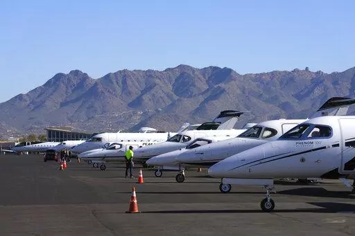 A Scottsdale Airport staffer waits on a private jet, as the airport gears up for the expected dramactic increase in private jet traffic, leading up to the NFL Super Bowl LVII football game at Scottsdale Airport in Scottsdale, Ariz., Thursday, Feb. 2, 2023. (AP Photo/Ross D. Franklin)