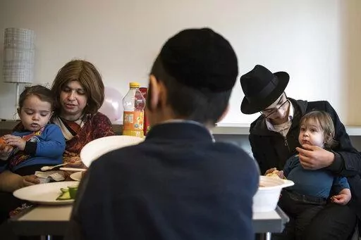 Children and their companions from an orphanage in Odesa, Ukraine, eat after their arrival at a hotel in Berlin, Friday, March 4, 2022. More than 100 Jewish refugee children who were evacuated from a foster care home in war-torn Ukraine and made their way across Europe by bus have arrived in Berlin. (AP Photo/Steffi Loos)