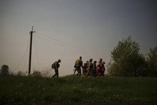 Ukrainian servicemen and emergency workers carry the body of a suspected Russian soldier in Malaya Rohan, a village retaken by Ukrainian forces on the outskirts of Kharkiv, Ukraine, Sunday, May 8, 2022. (AP Photo/Felipe Dana)