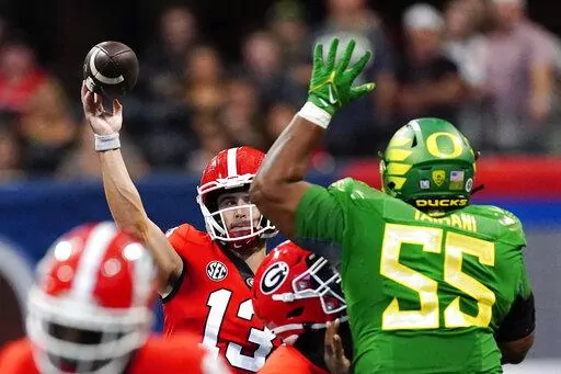 Georgia quarterback Stetson Bennett (13) throws under pressure from Oregon defensive lineman Taki Taimani (55) in the first half of an NCAA college football game Saturday, Sept. 3, 2022, in Atlanta. (AP Photo/John Bazemore)