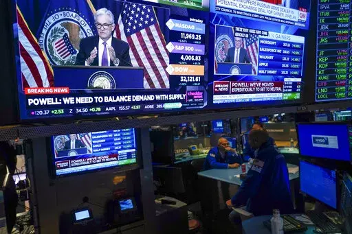 As traders work and watch, a news conference held by Federal Reserve Chair Jerome Powell is displayed at the New York Stock Exchange in New York, Wednesday, July 27, 2022. Stocks on Wall Street are solidly higher in afternoon trading Wednesday after the Federal Reserve raised its key interest rate by a widely expected three-quarters of a point as the central bank ratchets up its campaign to quell surging inflation. (AP Photo/Seth Wenig)