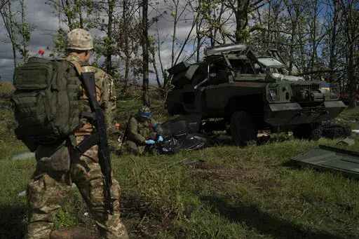 A Ukrainian national guard serviceman closes the bag containing the body of a Ukrainian soldier who was removed from an armored vehicle in an area near the border with Russia, in Kharkiv region, Ukraine, Monday, Sept. 19, 2022. This region of rolling fields and woodland near the Russian border was the site of fierce battles for months during the summer. Only now, after Ukrainian forces retook the area and pushed Russian troops back across the border in a blistering counteroffensive, has the coll