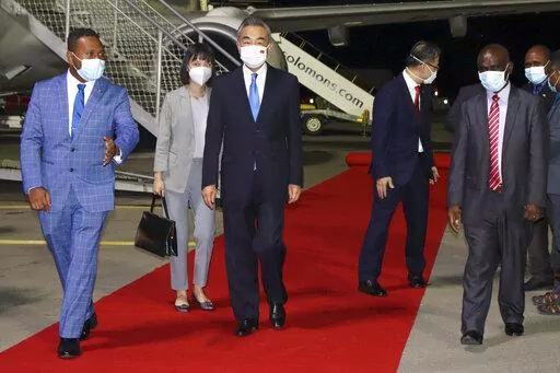 China's Foreign Minister Wang Yi, center, is escorted from his plane on his arrival in Honiara, Solomon Islands, early Thursday, May 26, 2022. Wang and a 20-strong delegation arrived in the Solomon Islands Thursday at the start of an eight-nation tour that comes amid growing concerns about Beijing’s military and financial ambitions in the South Pacific region. (AP Photo)