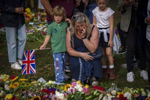 A woman cries next to flowers and messages for Queen Elizabeth II at the Green Park memorial, near Buckingham Palace, in London, Sept. 10, 2022. (AP Photo/Emilio Morenatti)