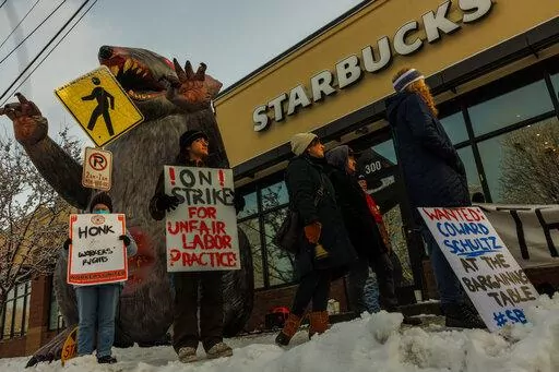 Starbucks workers hold signs in front of a giant inflatable rat during the "Unfair Labor Practice Strike." in St. Paul, Minn. on Friday, Dec. 16, 2022. Starbucks workers around the U.S. are planning a three-day strike starting Friday. The walkouts are part of their effort to unionize the coffee chain's stores.(Kerem Yücel /Minnesota Public Radio via AP)