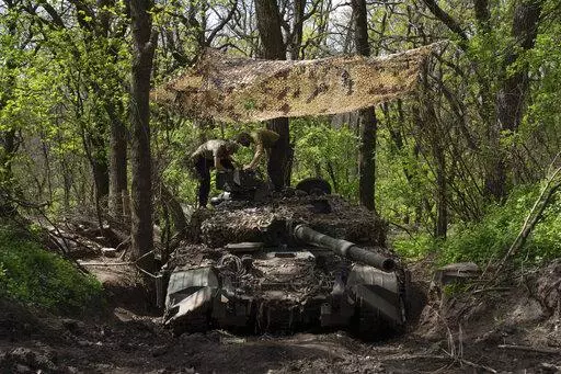 Ukrainian servicemen install a machine gun on the tank during the repair works after fighting against Russian forces in Donetsk region, eastern Ukraine, Wednesday, April 27, 2022. (AP Photo/Evgeniy Maloletka)