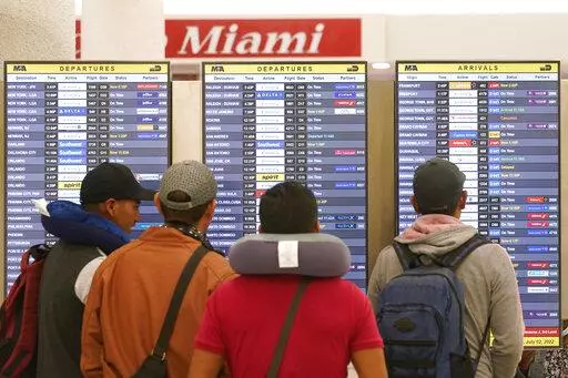 Travelers check their flights at Miami International Airport, Saturday, July 2, 2022, in Miami. The Fourth of July holiday weekend is jamming U.S. airports with the biggest crowds since the pandemic began in 2020. (AP Photo/Marta Lavandier)