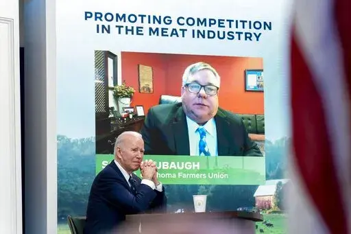 President Joe Biden attends a virtual meeting with family and independent farmers and ranchers including Scott Blubaugh, President, Oklahoma Farmers Union, visible on the monitor, at the South Court Auditorium in the Eisenhower Executive Office Building on the White House Campus in Washington, Monday, Jan. 3, 2022, to discuss work to boost competition and reduce prices in the meat-processing industry. (AP Photo/Andrew Harnik)