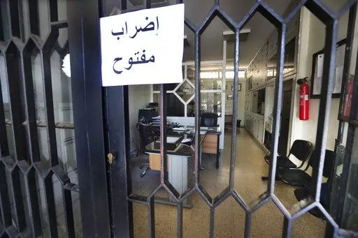 An Arabic placard reads: "Open strike", is posted on a door of an empty municipality office, in Bramiyeh, south Lebanon,  July 27, 2022. Tens of thousands of Lebanese public sector workers are on strike for a sixth week as they struggle to cope with the country's crippling economic crisis. (AP Photo/Mohammed Zaatari)