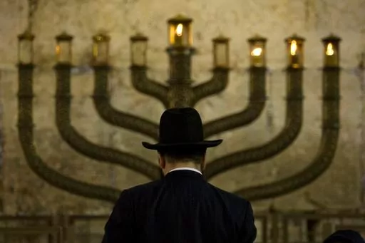 An Ultra-Orthodox Jewish man stands in front of a menorah on the third eve of Hanukkah, at the Western Wall, Judaism's holiest site in Jerusalem's old city, Sunday, Dec. 13, 2009. On eight consecutive nightfalls, Jews gather with family and friends to light one additional candle in the menorah candelabra. They do so to commemorate the rededication of the Temple in Jerusalem in the 2nd century BC, after a small group of Jewish fighters liberated it from occupying foreign forces. (AP Photo/Sebasti
