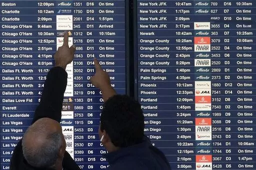 Two men point toward plane arrivals on a flight information board at San Francisco International Airport in San Francisco, Tuesday, Nov. 26, 2019.   Forecasters say, Friday, March 11, 2022,  a powerful, late-winter storm combining rivers of moisture and frigid temperatures is expected to dump snow from the Deep South all the way north to the Canadian border over the weekend that could cause travel problems and power outages across a wide part of the Eastern United States from late Friday through