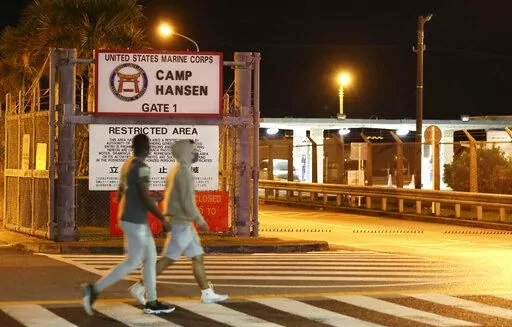 People walk. past the game of the U.S. Marine Corps' Camp Hansen, in Kin, Okinawa prefecture, southern Japan, on Jan. 6, 2022. Okinawa, a southwestern group of islands, which houses most of the 55,000 U.S. troops in Japan, is among the three prefectures where new restrictions to curb the spread of the coronavirus infections kicked in Sunday, Jan. 9.(Kyodo News via AP)