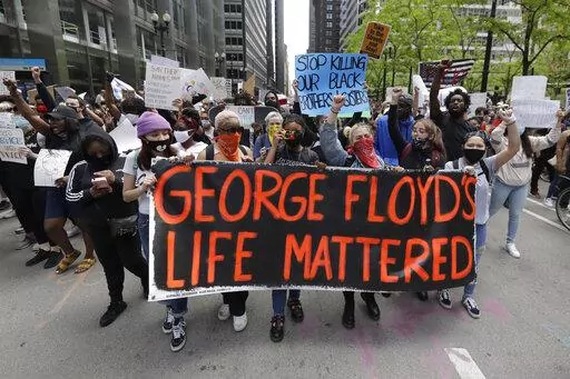 Protesters hold signs as they march during a protest over the death of George Floyd in Chicago on May 30, 2020. Two former Minneapolis police officers charged in Floyd's death are heading to trial on state aiding and abetting counts, the third and likely final criminal proceeding in a killing that mobilized protesters worldwide against racial injustice in policing. (AP Photo/Nam Y. Huh, File)
