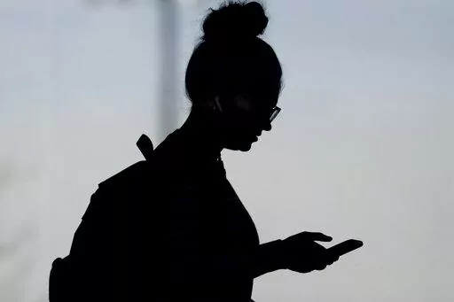 A woman checks her phone in Orem, Utah, on Nov. 14, 2019. A survey of people ages 16 to 40 finds that millennials and Generation Z follow the news, but they aren't that happy with what they're seeing. The study conducted by The Associated Press-NORC Center for Public Affairs Research and the American Press Institute says 79% of people follow news daily, contrary to perceptions that many are tuned out. (AP Photo/Rick Bowmer, File)