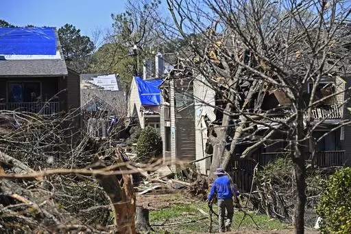 A man drags tree limbs to a pile at the Foxcroft Woods Condominiums, Sunday, April 2, 2023, in Little Rock, Ark. Residents across a wide swath of the U.S. raced to assess the destruction from fierce storms that spawned possibly dozens of tornadoes from the South and the Midwest into the Northeast, killing at least 32 people. (Staci Vandagriff/Arkansas Democrat-Gazette via AP)