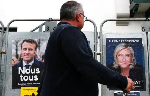 A man walks past presidential campaign posters of french president Emmanuel Macron and centrist candidate for reelection and french far-right presidential candidate Marine Le Pen in Anglet, southwestern France, Wednesday, April 8, 2022. France's first round of the presidential election takes place on April 10, with a presidential runoff on April 24 if no candidate wins outright. (AP Photo/Bob Edme)