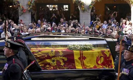 Members of the public look on a Queen Elizabeth II's coffin makes its way from the Palace of Holyroodhouse to St Giles' Cathedral, in Edinburgh, Monday, Sept. 12, 2022. King Charles III arrived in Edinburgh on Monday to accompany his late mother’s coffin on an emotion-charged procession through the historic heart of the Scottish capital to the cathedral where it will lie for 24 hours to allow the public to pay their last respects. (Andrew Milligan/Pool Photo via AP)