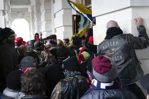 Insurrectionists loyal to President Donald Trump try to open a door of the U.S. Capitol as they riot in Washington, Jan. 6, 2021. Three active-duty Marines have been charged in the riot at the U.S. Capitol. Court records show that Micah Coomer, Joshua Abate and Dodge Dale Hellonen were arrested this week on misdemeanor charges after fellow Marines helped investigators identify them in footage among the pro-Trump mob on Jan. 6, 2021. (AP Photo/Jose Luis Magana, File)