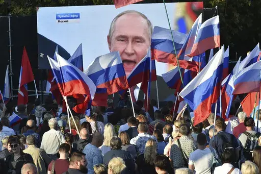 People watch as Russian President Vladimir Putin delivers a speech after signing treaties for four regions of Ukraine to join Russia in the Moscow's Kremlin, during a meeting in Sevastopol, Crimea, on Sept. 30, 2022. (AP Photo, File)