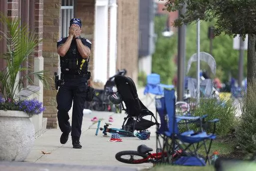 CORRECTS TO A LAKE FOREST POLICE OFFICER, INSTEAD OF LAKE COUNTY A Lake Forest, Ill., police officer walks down Central Ave in Highland Park, Ill., on Monday, July 4, 2022, after a shooter fired on the northern suburb's Fourth of July parade. (Brian Cassella/Chicago Tribune via AP)