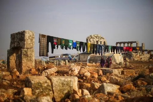 Syrian displaced people walk next to ancient Roman era ruins where they have set their tends in Sarmada district, north of Idlib city, Syria, Thursday, Nov. 25, 2021.  Fallout from the 2-month-old war in Ukraine is worsening long-term humanitarian crises elsewhere, including in Syria.  (AP Photo/Francisco Seco, File)