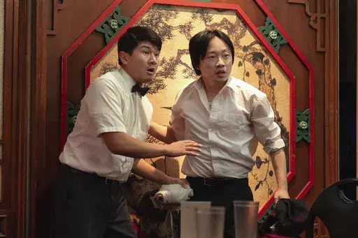 This image released by Hulu shows Jimmy O. Yang, right, and Ronny Chieng in a scene from the series "Interior Chinatown." (Mike Taing/Hulu via AP)