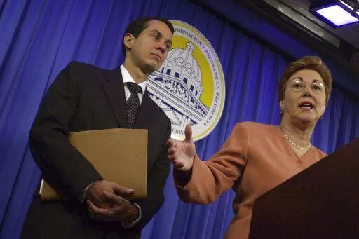 Dominican Secretary for Commerce and Industry Sonia Guzman, right, talks to the media accompanied by Orlando Jorge Mera, at the presidential palace in Santo Domingo, Dominican Republic, March 16, 2004. Mera, the Dominican Republic’s minister of the environment and natural resources, was shot and killed in his office on Monday, June 6, 2022, according to officials. (AP Photo/Walter Astrada, File)