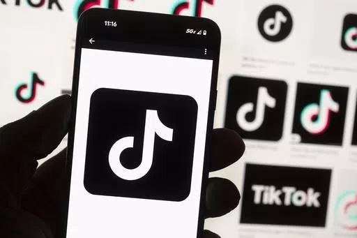The TikTok logo is displayed on a mobile phone in front of a computer screen, Oct. 14, 2022, in Boston. TikTok will begin labeling content created using artificial intelligence when it's uploaded from certain platforms. TikTok says its efforts are an attempt to combat misinformation from being spread on its social media platform. The announcement came on ABC's “Good Morning America” on Thursday, May 9, 2024. (AP Photo/Michael Dwyer, File)