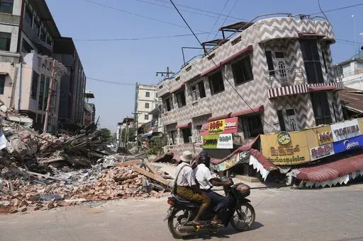 A local man drives a motorbike past damaged buildings in the aftermath of an earthquake in Naypyitaw, Myanmar, Sunday, March 30, 2025. (AP Photo/Aung Shine Oo)