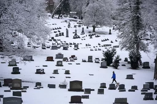 A man walks through the snow covered Mount Lebanon Cemetery in Mount Lebanon, Pa., on Monday, Jan. 23, 2023. U.S. deaths fell in 2022, as COVID-19 fatalities dropped by half from 2021 and the coronavirus dropped from being the nation's third leading cause of death to the fourth. The Centers for Disease Control and Prevention reported the 2022 numbers on Thursday, May 4, 2023, cautioning that they are preliminary and may change a little after further analysis. (AP Photo/Gene J. Puskar, File)