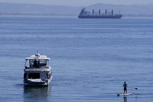 A person paddle boards near a boat in McCovey Cove in San Francisco, Sunday, Sept. 4, 2022. (AP Photo/Jeff Chiu)